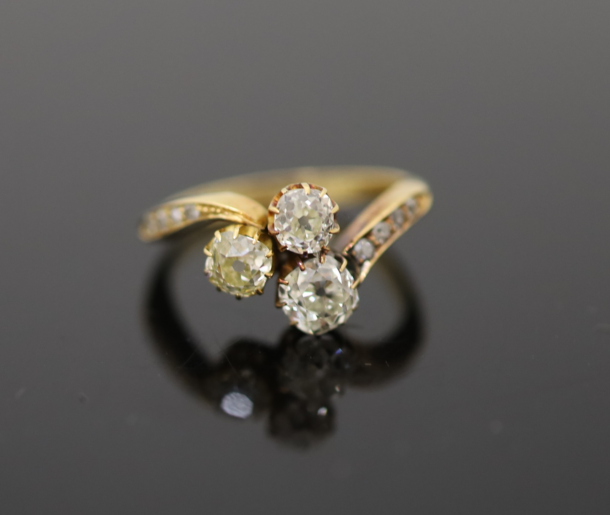 An Edwardian 18ct gold and three stone set clover shaped cluster ring